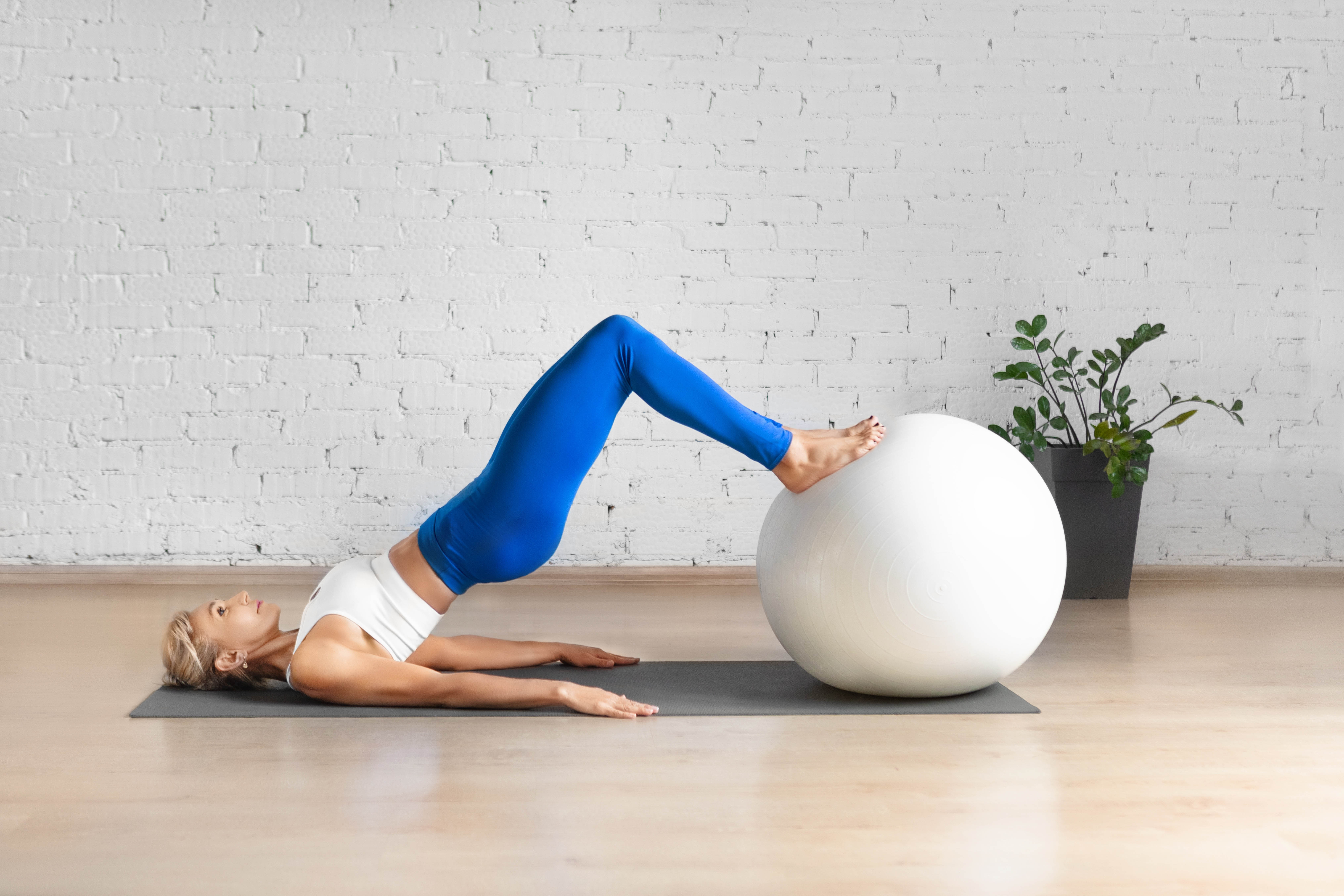 Woman doing a pelvic health exercise with her balance ball and lying on the floor Woman doing a pelvic health exercise with her balance ball and lying on the floor